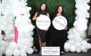 Mon Amie CEO Laurel (L) and Sales Manager Betzi holding the boutique&rsquo;s three different choices
of signs for when a bride says yes, in front of its photo wall.