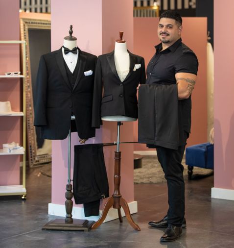 Marketing Manager Sidney DeJesus works on a display featuring suits from Robert Paul’s San Francisco store at Janene’s Bridal in Alameda.