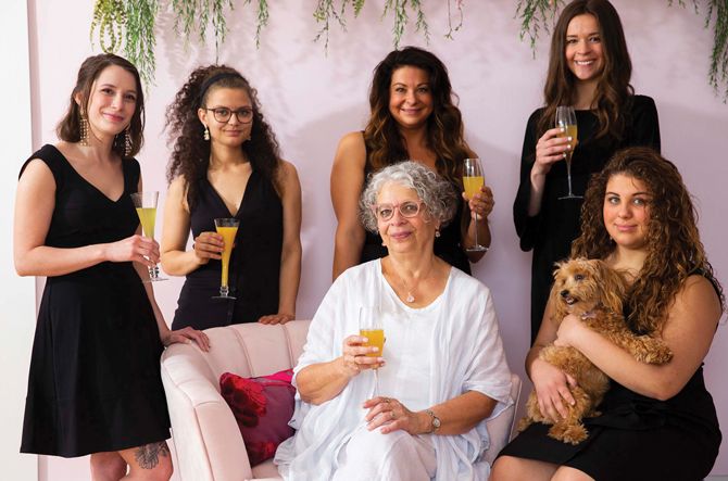 The Fiori Bridal Boutique Team (Back, L to R): Anna, Jasmn, Erin (Geri’s daughter), Karsyn (Geri’s granddaughter). Seated: Owner Geri Cardinal and Lily (Erin’s daughter/Geri’s granddaughter, holding shop dog Gracie).