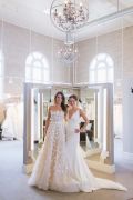 Full-length lights over the three-way mirrors at Little White Dress Bridal Shop in Denver prevent shadows on the dresses, while chandeliers show off the high ceilings and large space of the salon.