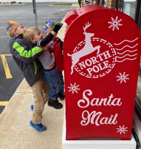Two children mail their letters to the North Pole during pandemic times, when Santa events were canceled due to health and safety precautions.