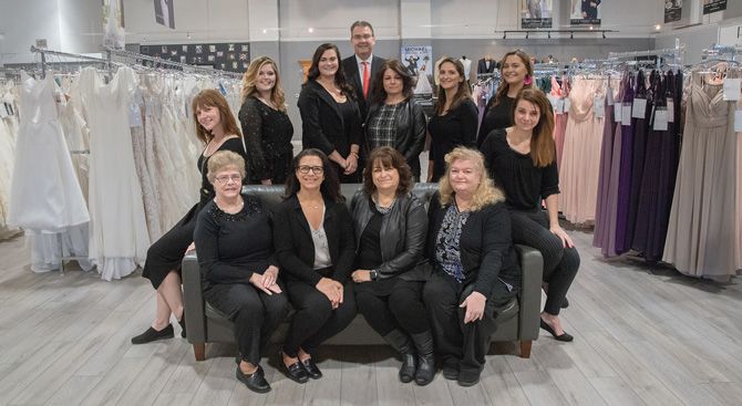 The Modern Bride & Formal Shop staff. Seated: Cecile Houle (seamstress), Renee Fortin (owner), Debbie Fortin (sister-in-law/consultant), Donna Dominick (seamstress). Back Row: Consultants Anna Jefferies, Michayla Hernden, Lauren Cordts, Brian Fortin (owner), Danielle Willette, Delaney Procaccini, Tayler Rodgers,
Courtney Collins.